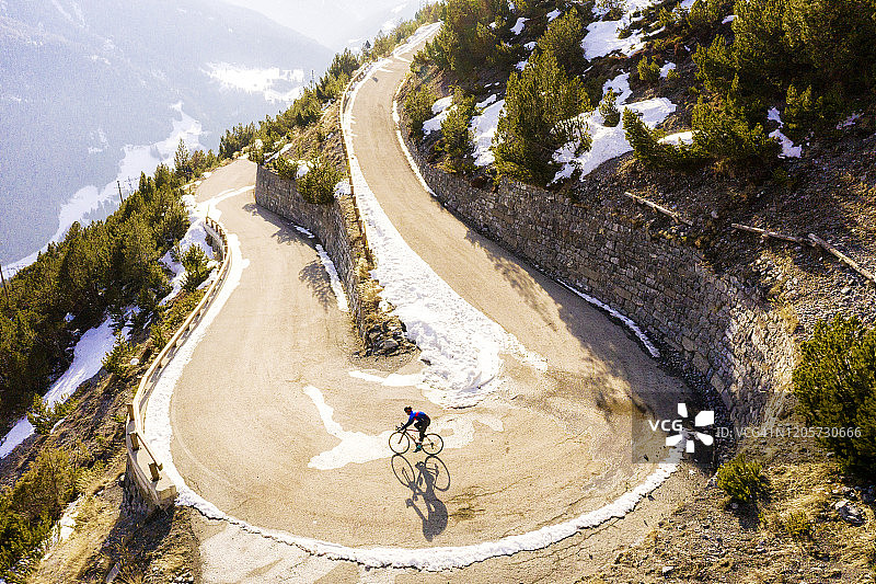 骑行者在冬季从高山弯曲的道路上滑下图片素材