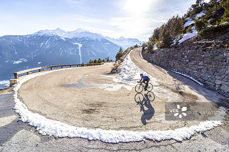 骑行者在冬季从高山弯曲的道路上滑下图片素材