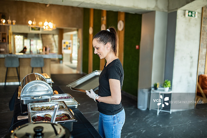 女人在自助餐前准备餐桌图片素材