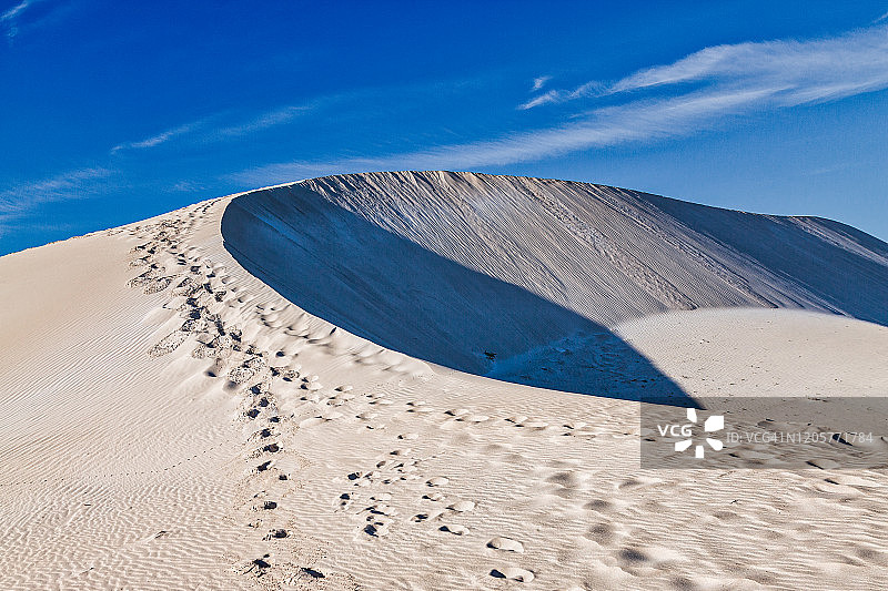 蓝色天空下沙丘顶部的脚印图片素材