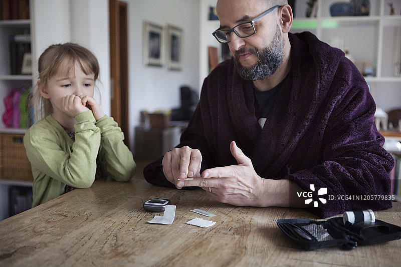 父母教孩子用血糖仪监测糖尿病图片素材