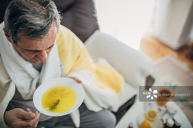 生病的男人喝热汤图片素材