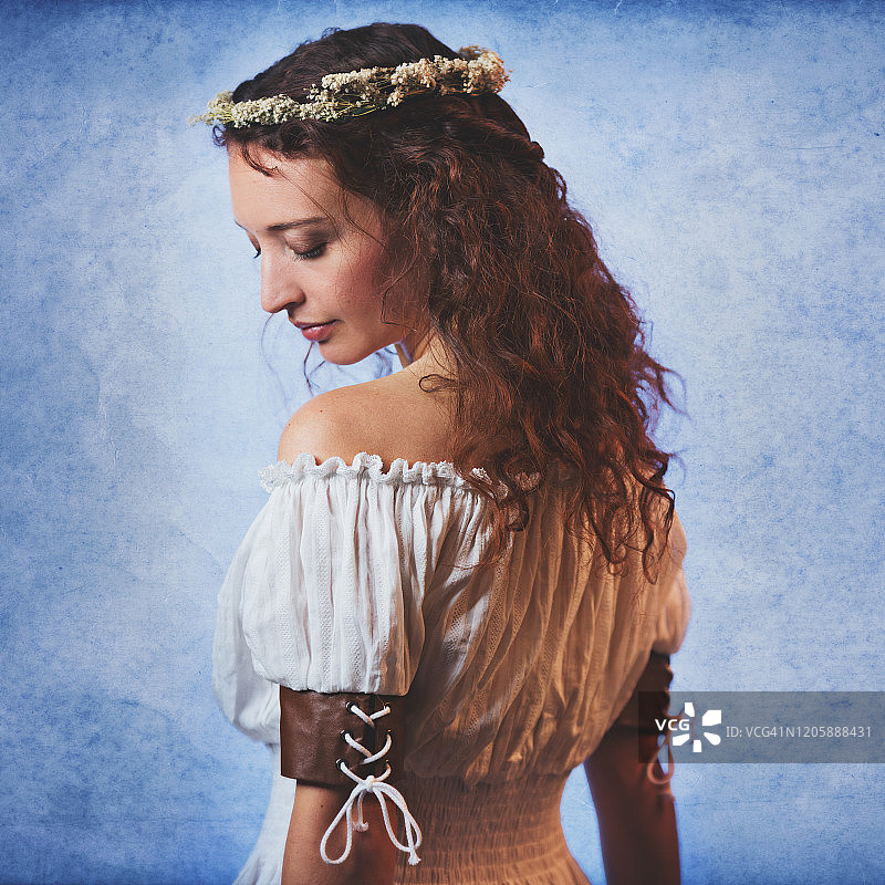 穿着露肩女衫、头戴花冠的红色波浪长发年轻女子图片素材