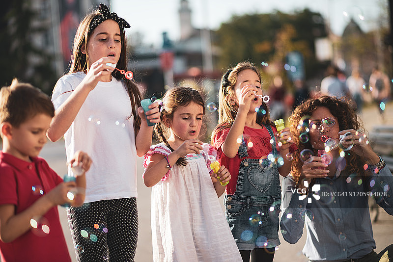 快乐的孩子们在城市街道吹泡泡图片素材