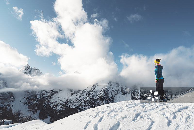 孤独的徒步者站在雪地里欣赏山景图片素材
