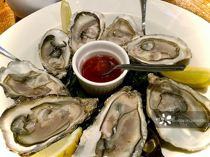 冰上搭配柠檬和法式酱汁的新鲜去壳牡蛎图片素材