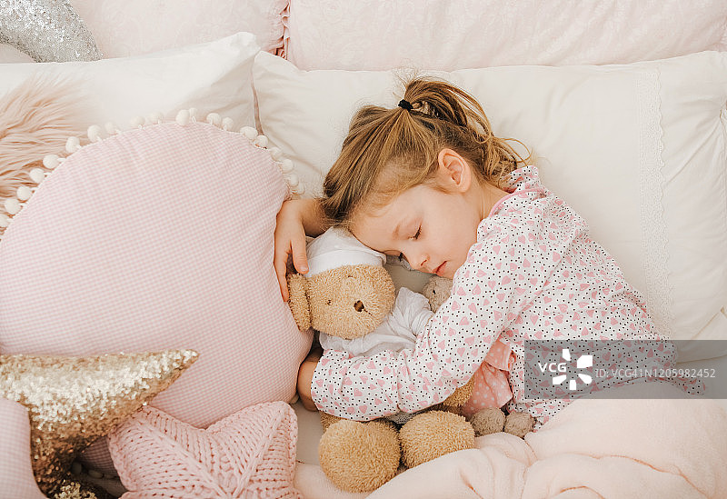 小女孩和玩具泰迪熊在床上睡觉图片素材