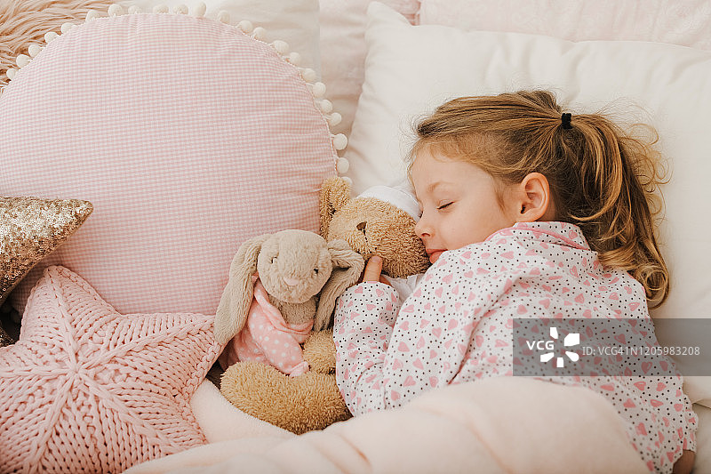 小女孩和玩具泰迪熊在床上睡觉图片素材