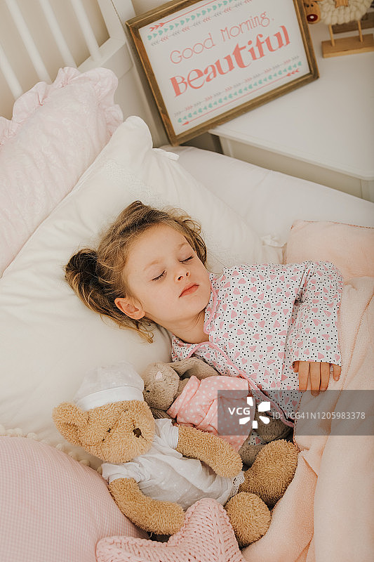 小女孩和玩具泰迪熊在床上睡觉图片素材