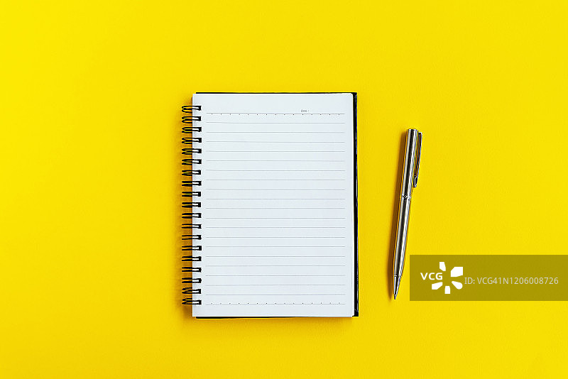 黄色背景上的便签本和笔图片素材