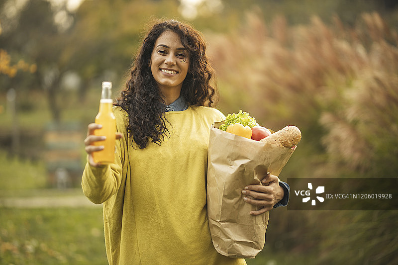 妇女拿着果汁和装满食品的纸袋的肖像图片素材