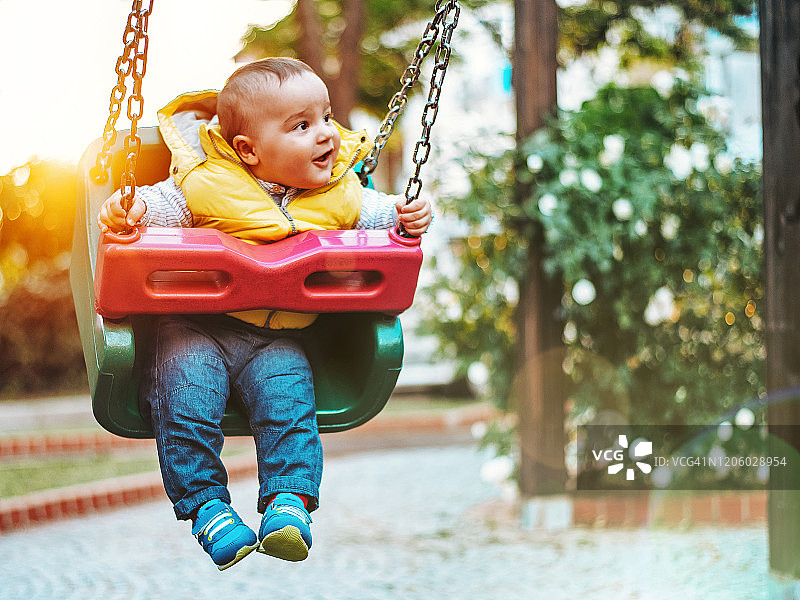 在游乐场秋千上玩耍的快乐男婴图片素材