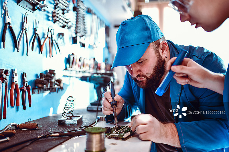 男性学徒帮助机械师焊接零件图片素材