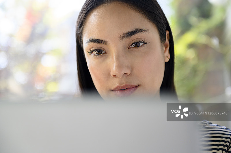 在笔记本电脑后面的黑发女人图片素材