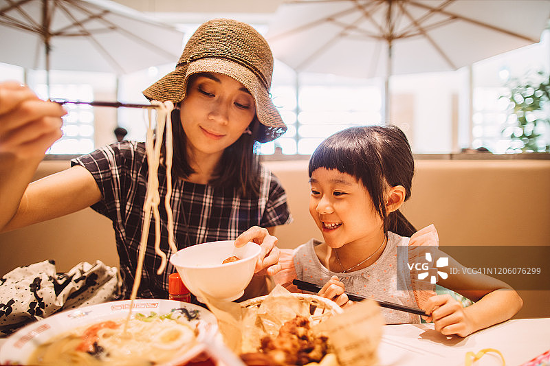 年轻漂亮的妈妈和可爱的女儿在餐厅用餐图片素材