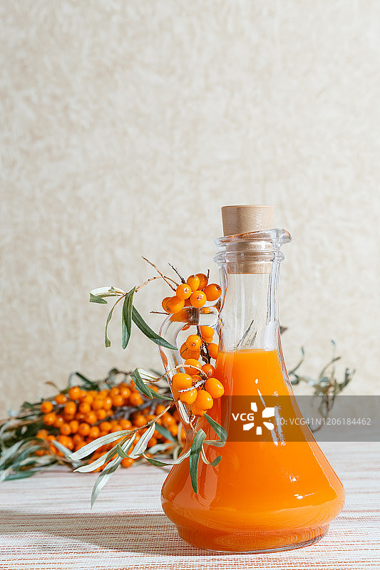 素食、健康营养。自制成熟多汁沙棘的丰收，准备新鲜健康维生素饮料和治疗汤。瓶装果汁和橙色沙棘枝图片素材