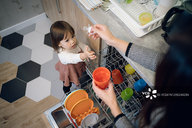 可爱的小女孩帮助她的母亲收拾碗碟图片素材