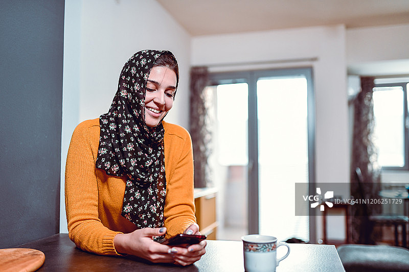 现代穆斯林女性与朋友发短信喝咖啡图片素材