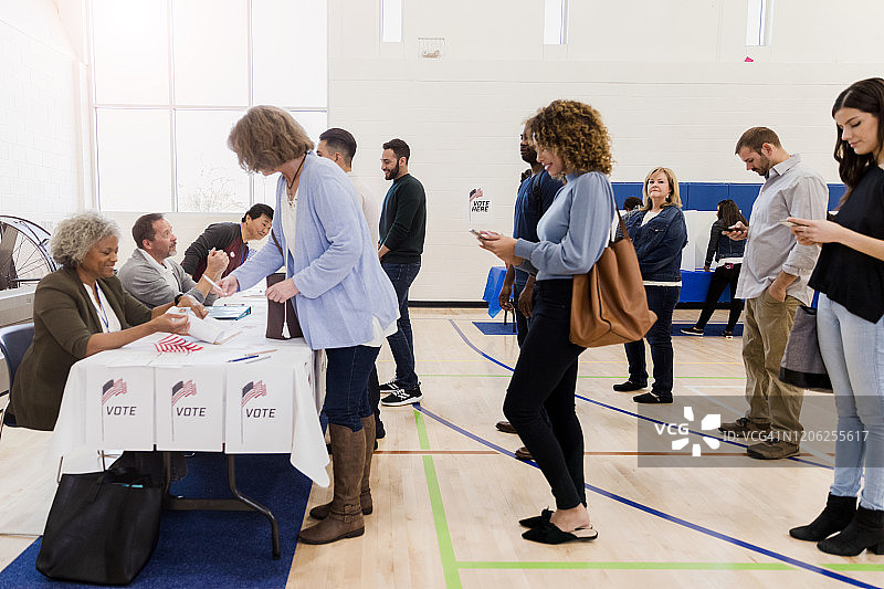 等待投票时使用智能手机的人们图片素材