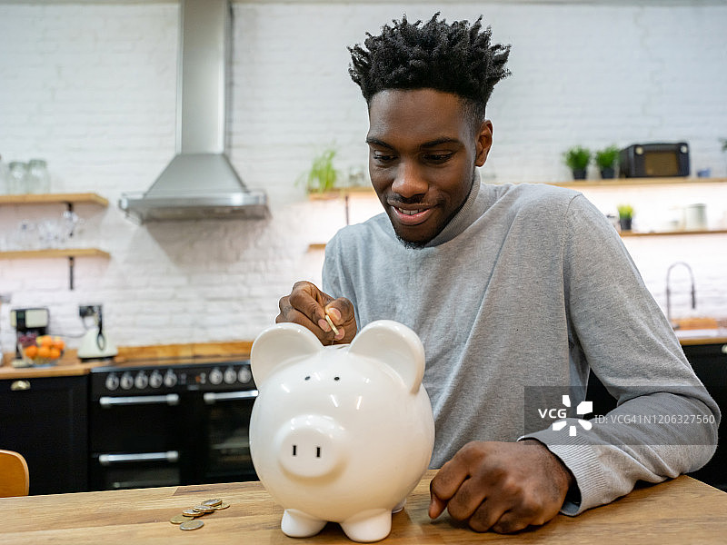 居家男人往存钱罐里存钱图片素材