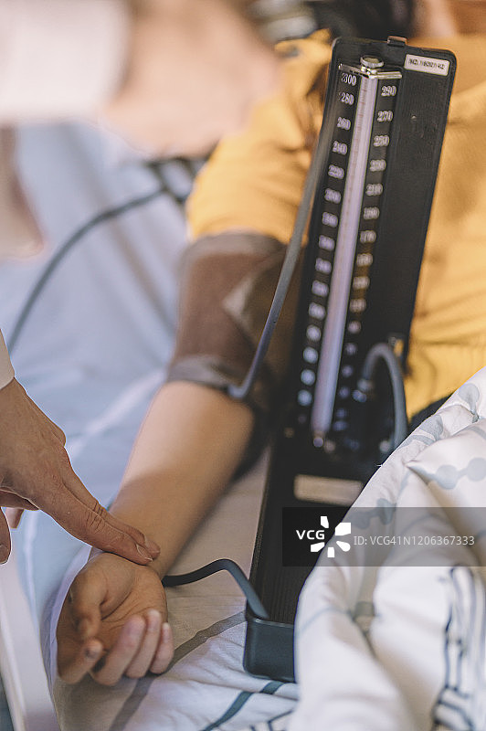 华人男医生在医院病房里为女病人量血压图片素材