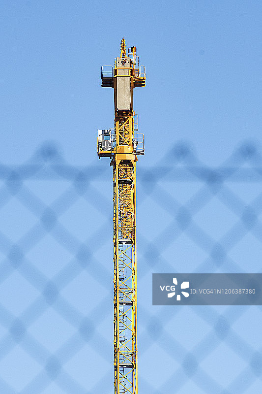 围栏另一侧的黄色起重机图片素材