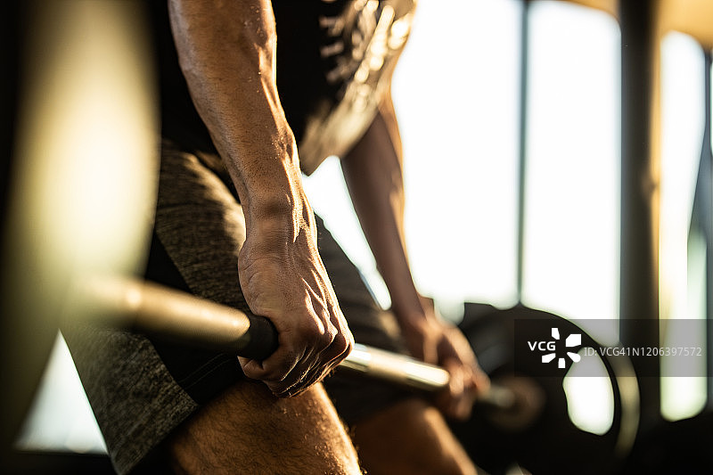 健身房内，一位身份不明的男运动员正在练习硬举特写图片素材