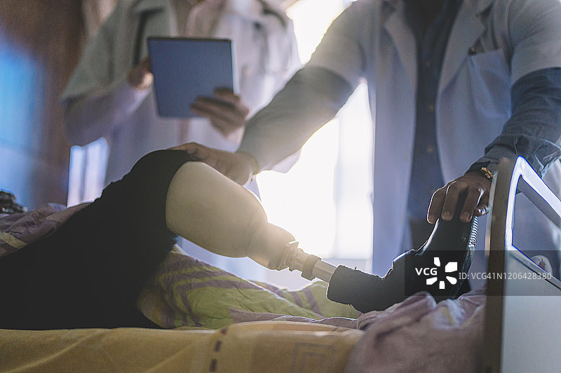 两位华人医生在医院病房里与安装假肢的印度女病人讨论病情图片素材