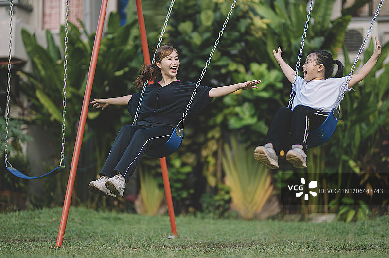 中国母亲在公园和女儿玩秋千图片素材