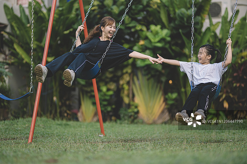 中国母亲在公园和女儿玩秋千图片素材