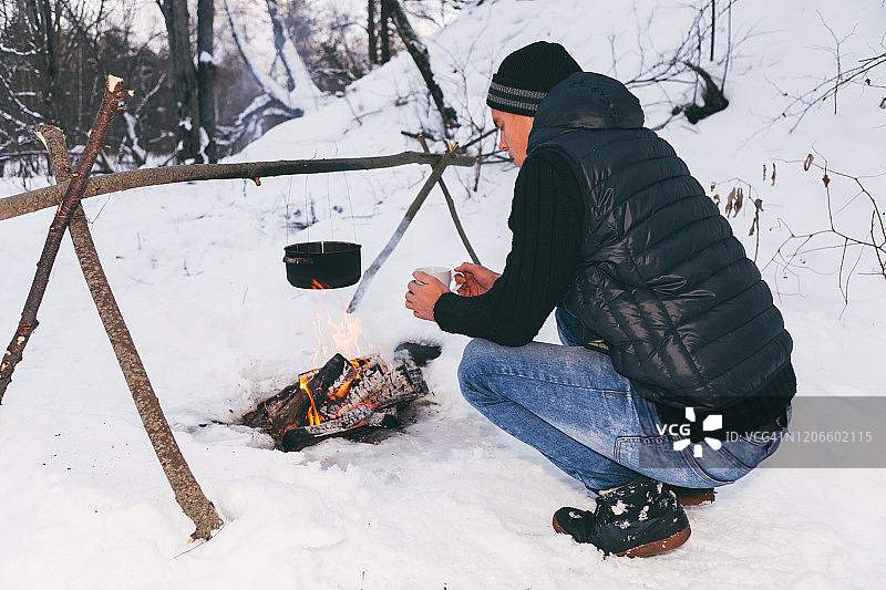 男子准备生火并烧水做饭，冬季露营图片素材