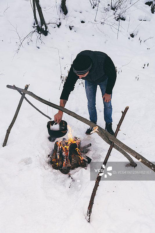 男子准备生火并烧水做饭，冬季露营图片素材