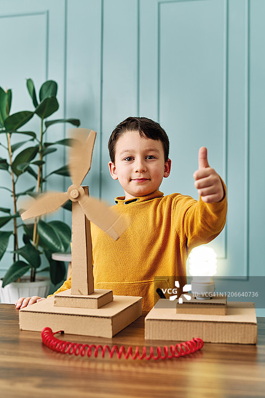 可爱儿童发明清洁能源风力涡轮机，风力转动点亮灯泡图片素材