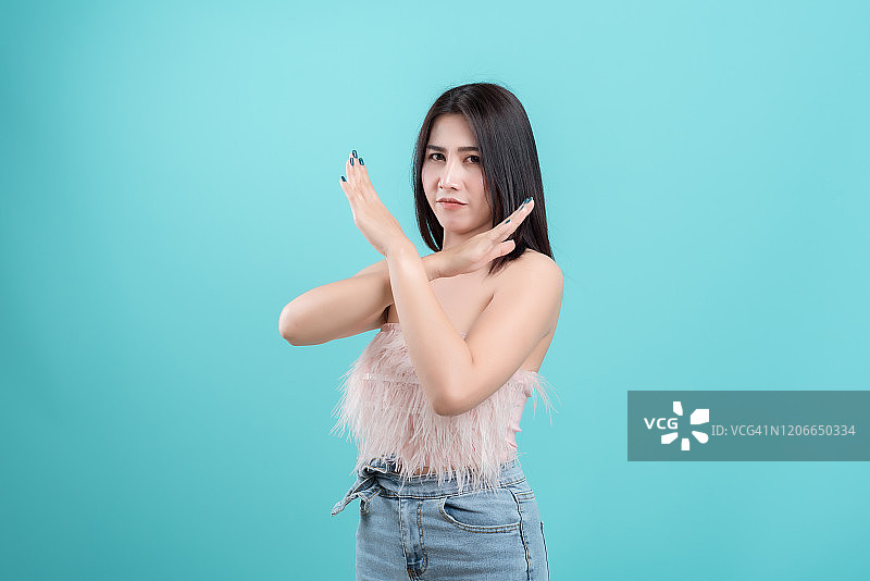 请不要！一位女士在蓝色背景下对着镜头做出交叉手势的特写照片图片素材