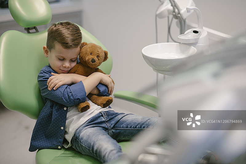 孩子在牙医诊所和泰迪熊玩牙刷图片素材