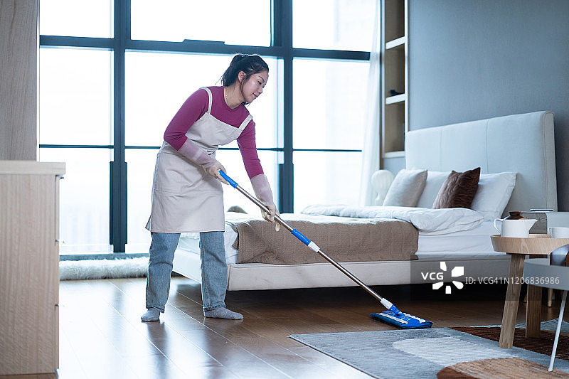 亚洲女人用拖把清洁地板图片素材