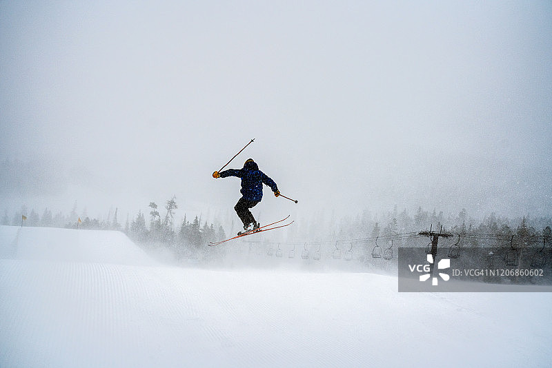 年轻男子在雪地自信地进行极限自由式滑雪跳跃图片素材