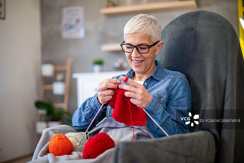 面带微笑的中年妇女在做一条温暖的冬季围巾图片素材