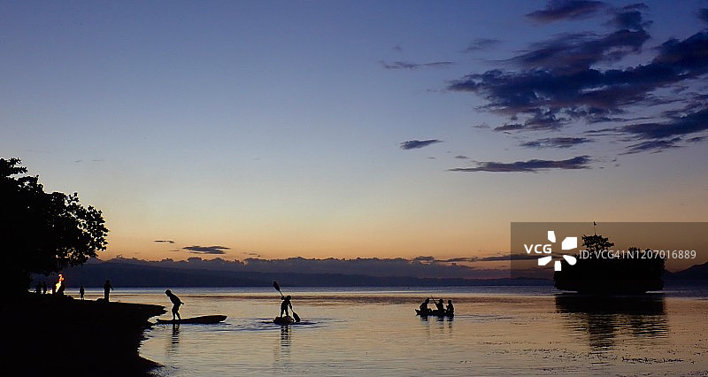 在日落时分海洋上划桨的人们图片素材
