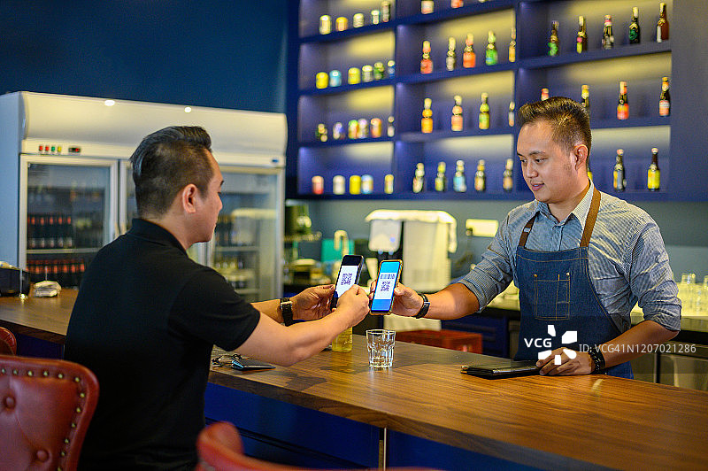 顾客在咖啡馆用智能手机扫描二维码进行便捷的非接触式支付图片素材