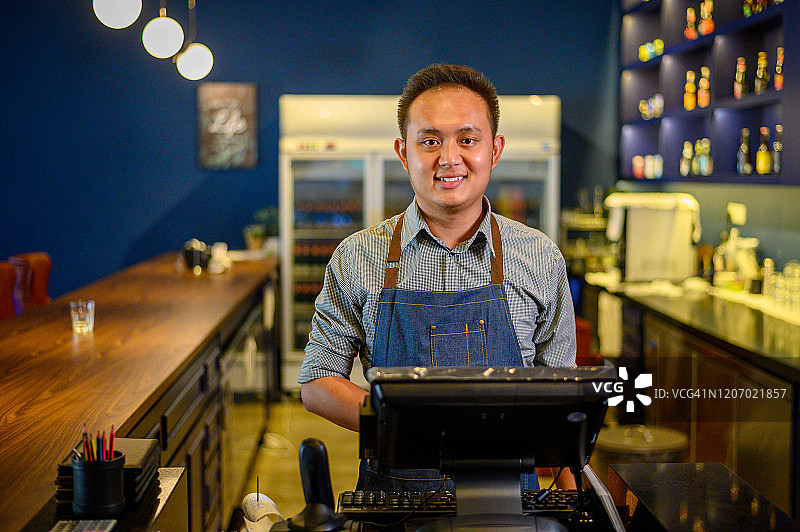 在咖啡馆柜台后工作的自豪亚裔男人图片素材