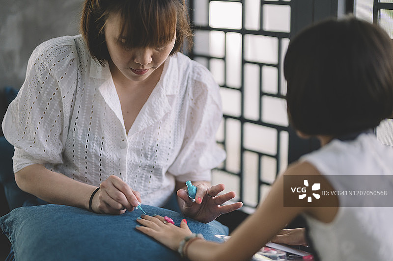 周末休闲时，中国母亲在家与女儿共度时光，一起涂指甲油图片素材