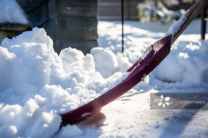 用红色铲子从路面铲雪图片素材