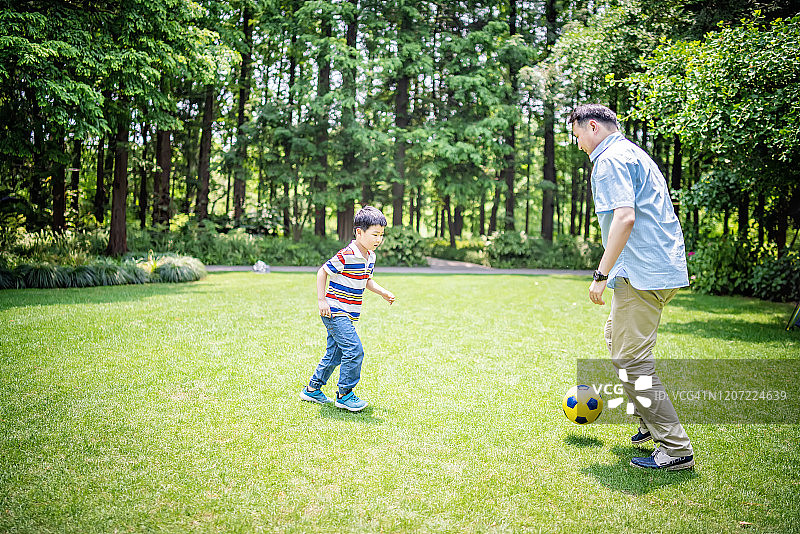 父亲和儿子在公园踢足球图片素材
