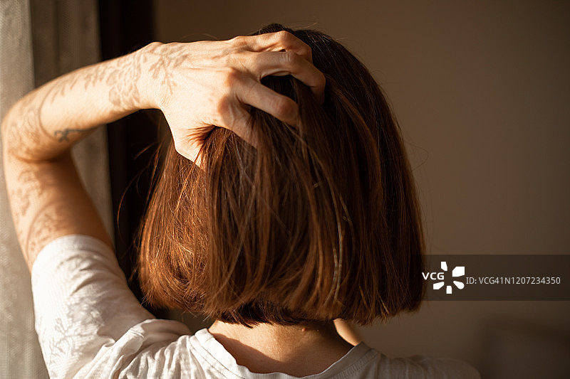 一位留着波波头、抱着头的女人的背影图片素材