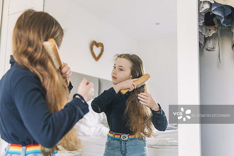 年轻女孩在镜子前梳头图片素材