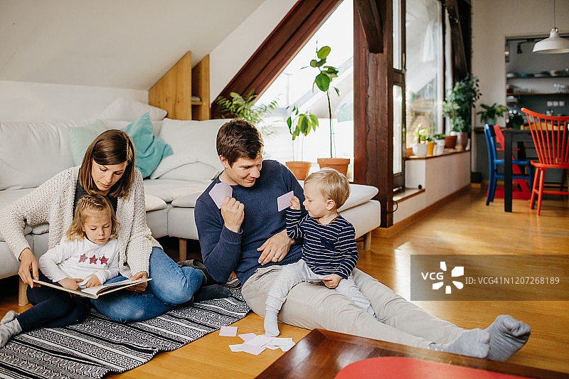 母亲和女儿一起读书，父亲和儿子一起玩牌图片素材