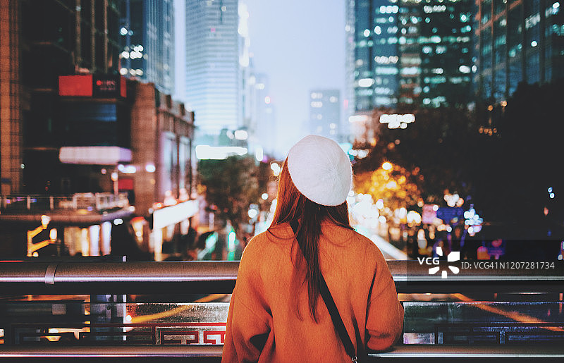 年轻女子站在城市夜间的桥上图片素材