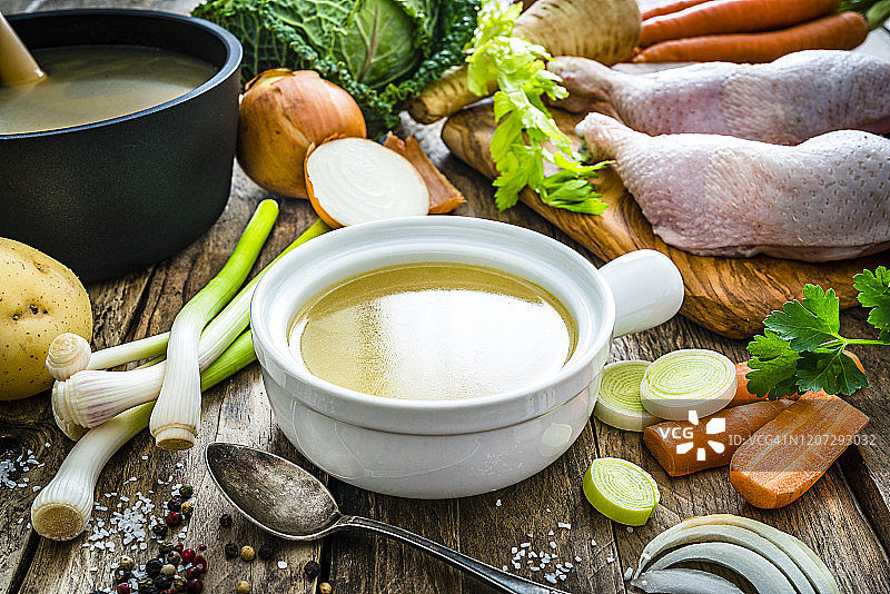 碗中的鸡汤和木制厨房桌上的食材图片素材