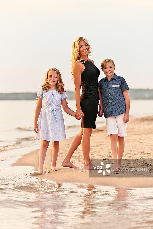 年轻母亲和孩子们在日落时分的海滩上合影图片素材